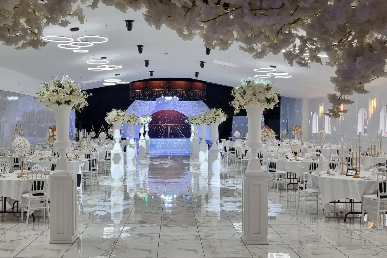 L'allée centrale du Luxury : colonnes blanches fleuries, voûte de fleurs et l'arche de l'estrade au fond